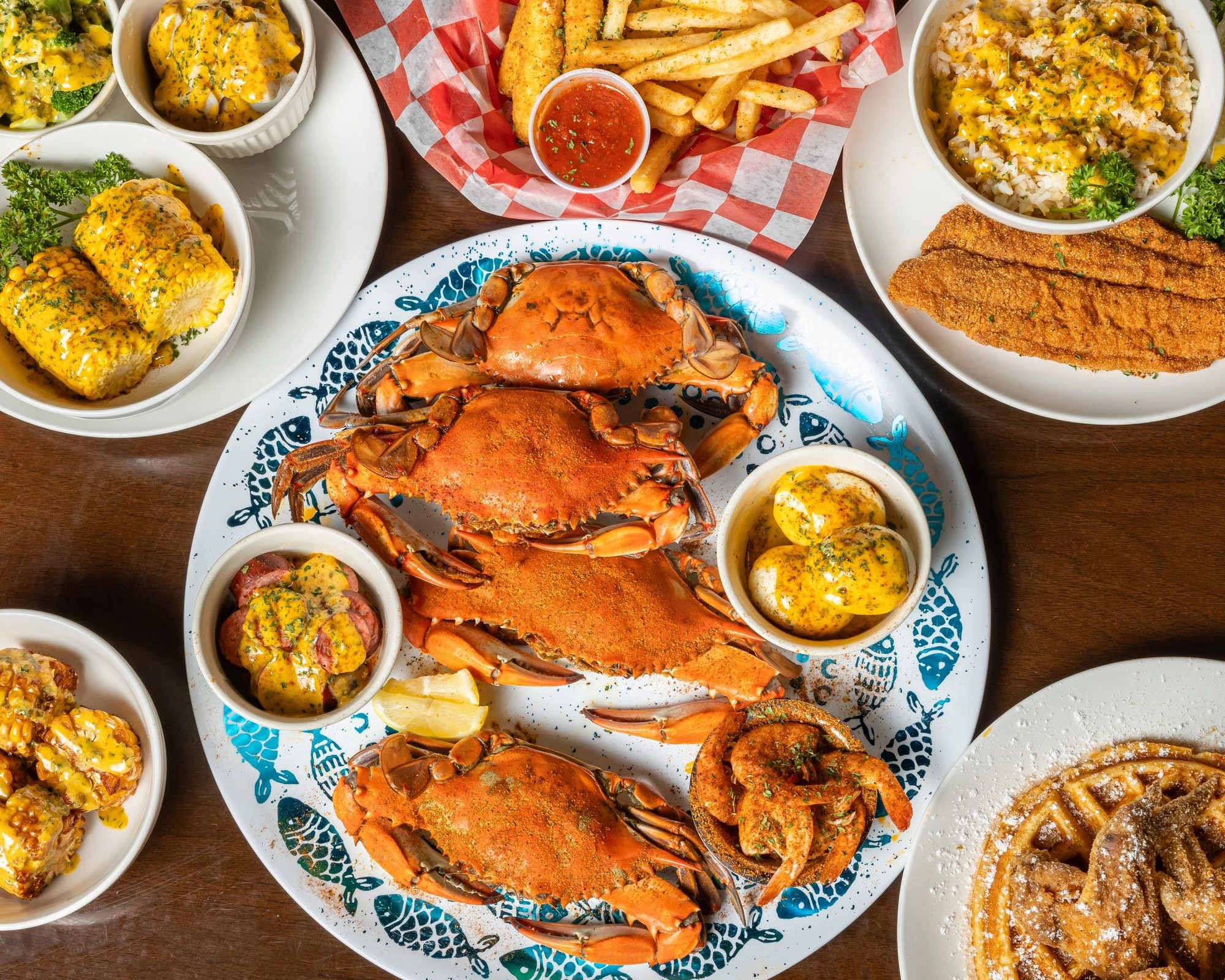 A table of blue crabs, fried fish, wings, fries and sides